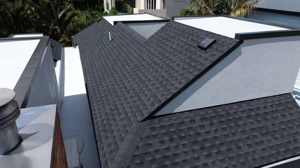 Close view of a dark grey asphalt shingle roof with valley flashing on a modern Auckland home